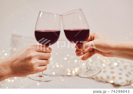 Hands of a man and a woman are holding glasses of wine. Romantic atmosphere, soft focus, bokeh, close-up 74299043