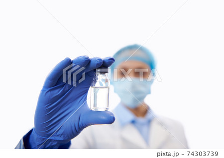 Development and creation of vaccine. Doctor holding a transparent bottle with vaccine and showing it to the camera. Isolated white background 74303739