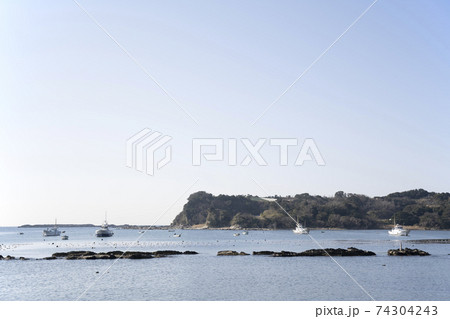神奈川県三浦市江奈湾に浮かぶ釣り船と岩礁の風景 74304243