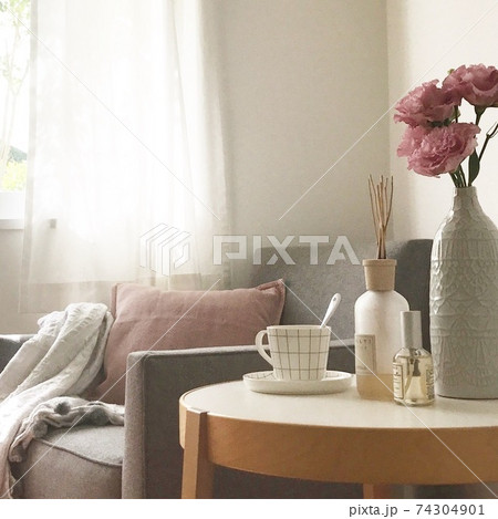 窓際のソファとカップとお花が置かれたテーブルの写真素材