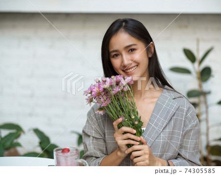 Beautiful female hand pink flowers brunch and smiling to camera 74305585