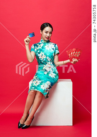 Asian woman in oriental cheongsam presenting red envelope and credit card 74305758