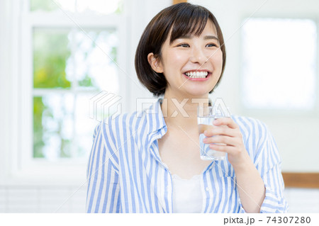 若い女性が水が入っているコップを持つ 若い女性が水が入っているコップを持つ 74307280