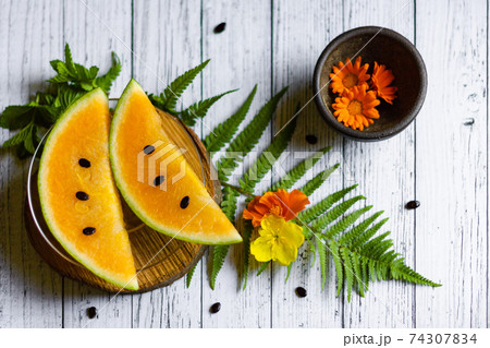 Sweet yellow water melon slices with seeds and flowers, top view Sweet yellow water melon slices with seeds and flowers, top view 74307834