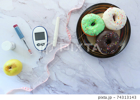diabetic measurement tools, insulin and donuts on white background  74313143