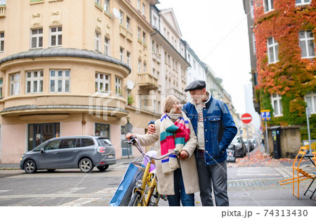 Happy senior couple with bicycle outdoors on street in city. 74313430