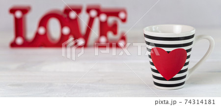 Stripy black and white cup with red heart on white background. Valentine's Day Cup. Love Concept 74314181