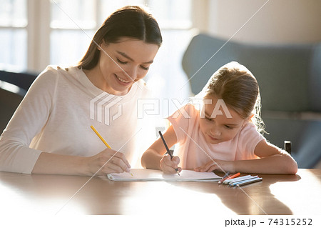 Happy young mom and little daughter draw in album 74315252