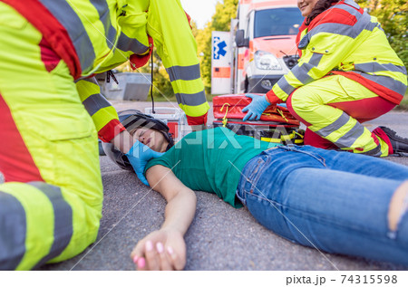 Paramedics removing helmet of injured motorcyclist after an accident 74315598