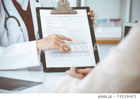 Unknown woman-doctor consulting patient and using clipboard with a medication history record. Medicine concept 74316425