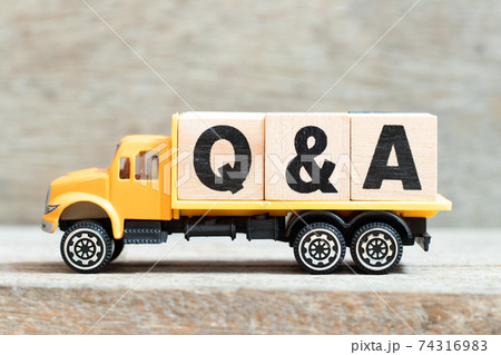 Toy truck hold alphabet letter block in word Q&A (Abbreviation of question and answer) on wood background 74316983
