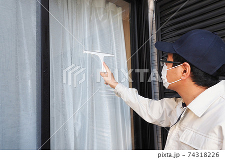 ガラス窓の清掃をするハウスクリーニング の男性作業員 74318226