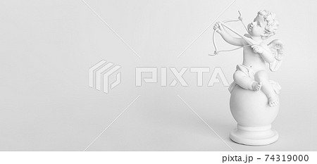 Banner. figurine of an angel Cupid with a bow on a pink background. Valentine's Day. 74319000
