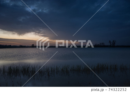 Dark evening clouds at the lake with reeds 74322252