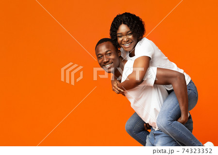 Funny black lovers posing on orange studio background Funny black lovers posing on orange studio background 74323352