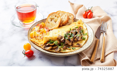 Omelet with champignons and parsley in plate on marble background. Frittata - italian omelet Omelet with champignons and parsley in plate on marble background. Frittata - italian omelet 74325887