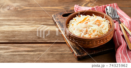 Sauerkraut, fermented cabbage with carrots in bowl on wooden background with copy space. 74325962