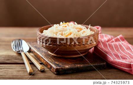 Sauerkraut, fermented cabbage with carrots in bowl on wooden background with copy space. Sauerkraut, fermented cabbage with carrots in bowl on wooden background with copy space. 74325973