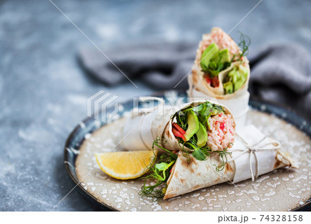 Fresh and healthy wrapped tortilla with crab salad, cucumber, avocado, pepper and green herbs 74328158