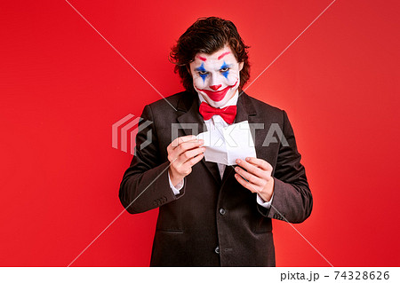 handsome male magician performing a trick with hands isolated on red background handsome male magician performing a trick with hands isolated on red background 74328626