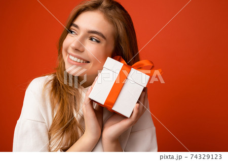 Closeup portrait photo of beautiful happy blonde young female person isolated over orange background 74329123