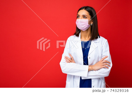 Young beautiful brunette woman in virus protective mask on face against coronavirus and white Young beautiful brunette woman in virus protective mask on face against coronavirus and white 74329316