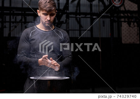 caucasian young athlete getting ready for weight lifting training, use talc caucasian young athlete getting ready for weight lifting training, use talc 74329740