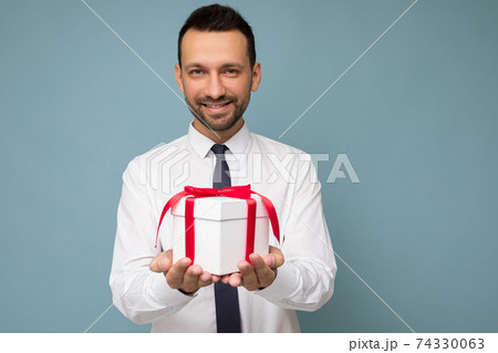 Photo shot of handsome positive brunette young unshaven businessman with beard isolated over blue 74330063