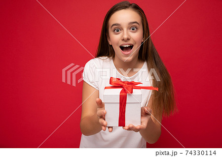 Photo shot of attractive happy delightful brunette girl isolated over red background wall wearing Photo shot of attractive happy delightful brunette girl isolated over red background wall wearing 74330114