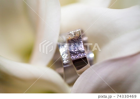 Close view on calla flowers with wedding rings in warm colors 74330469