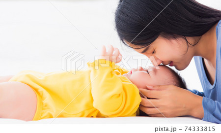mother kissing her infant newborn baby in a white bed 74333815