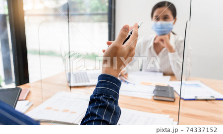 business team brainstorm they are working hard by looking through the plastic protective wall, concept of social distancing to prevent the spread of coronavirus COVID-19 74337152