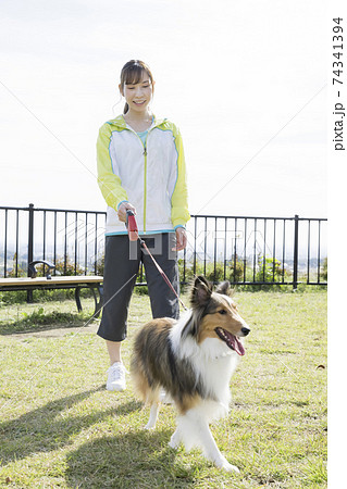 公園で犬の散歩をする若い女性 74341394