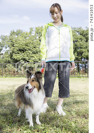 公園で犬の散歩をする若い女性 公園で犬の散歩をする若い女性 74341653
