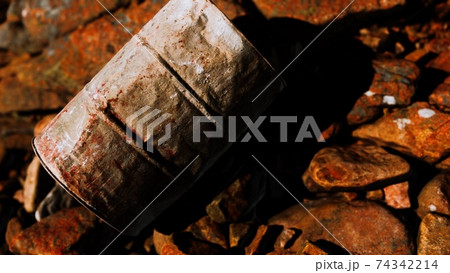 rusty destroyed metal barrel on beach rocks 74342214