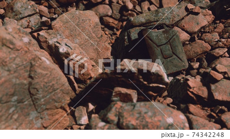 Old rusty metal canister for gasoline fuel at rocks 74342248