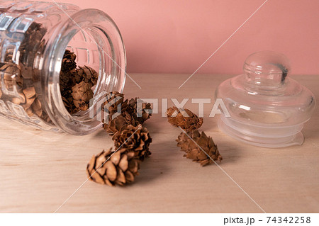 ガラス瓶からこぼれ出た小さな松ぼっくり - サイドから 74342258
