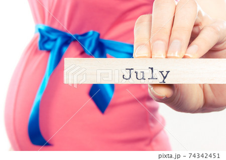 Pregnant woman in pink dress with blue ribbon showing word july 74342451