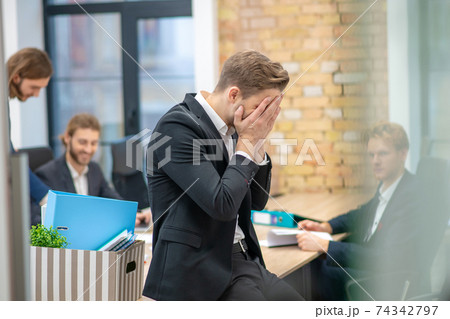 Man covering his face with hands sitting in office 74342797
