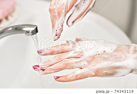 Young woman washing her hands under water tap faucet with soap. Detail on suds covered skin. Personal hygiene concept - coronavirus covid-19 outbreak prevention 74343119