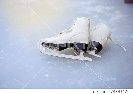 A pair of curly female skates lies on the ice at the rink A pair of curly female skates lies on the ice at the rink 74343120