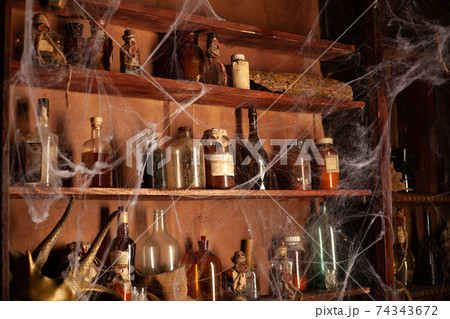 Halloween background Shelves with alchemy tools Skull spiderweb bottle with poison candles Halloween background Shelves with alchemy tools Skull spiderweb bottle with poison candles 74343672