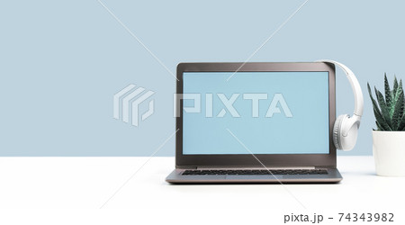 Laptop with wireless headphones on white desk Laptop with wireless headphones on white desk 74343982