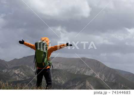 Successful woman backpacker open arms on high altitude mountain top Successful woman backpacker open arms on high altitude mountain top 74344685