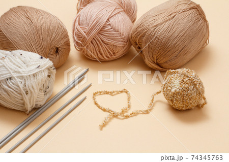 Woolen yarns for knitting. Balls of natural wool yarn and knitting needles. Woolen yarns for knitting. Balls of natural wool yarn and knitting needles. 74345763
