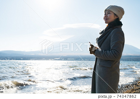 冬の山中湖湖畔をスマホのカメラで撮影する女性 冬の山中湖湖畔をスマホのカメラで撮影する女性 74347862