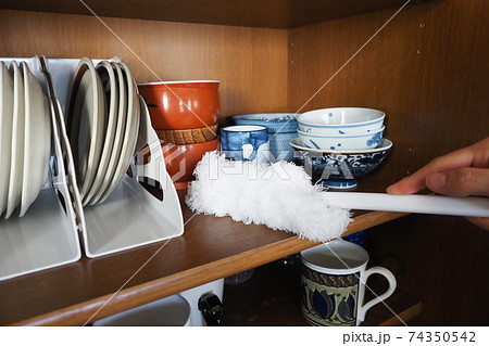 食器棚をモップで掃除する人の手元 74350542