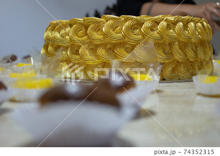 Golden birthday cake covered in chantilly surrounded by sweeties 74352315