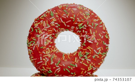 MACRO: Pink donut stands on a white dish MACRO: Pink donut stands on a white dish 74353107
