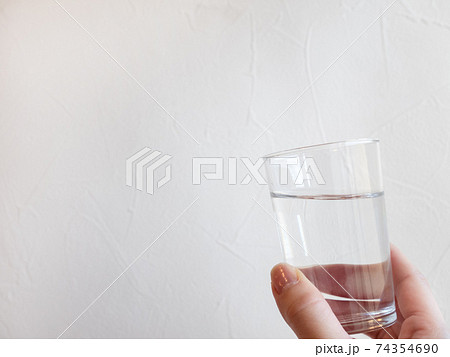 水が入った透明グラスを持つ手。水分補給、水を飲む。 74354690